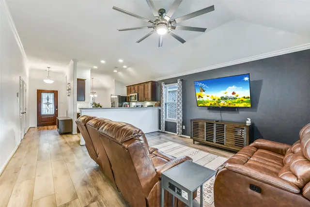 a living room with furniture and a flat screen tv with kitchen view