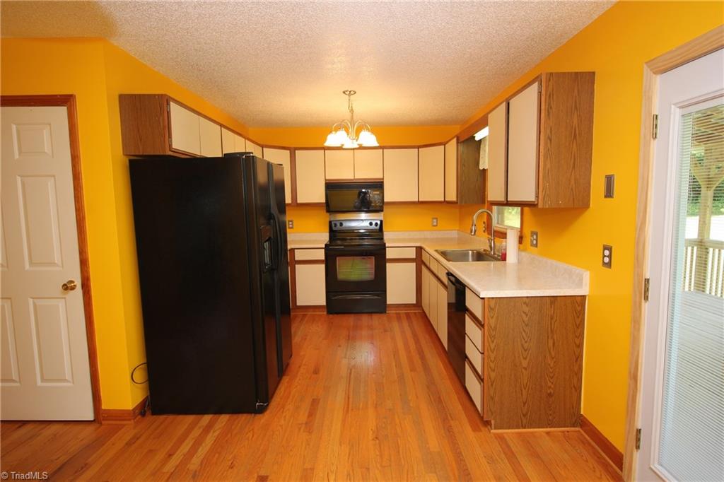 1164 County Home Road Mocksville, NC 27028 - Photo 3 of 18 Kitchen has a large pantry, hardwood floors. Refrigerator remains. Out the back door to the covered deck .