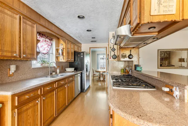 a kitchen with stainless steel appliances granite countertop a stove a sink dishwasher and cabinets with wooden floor
