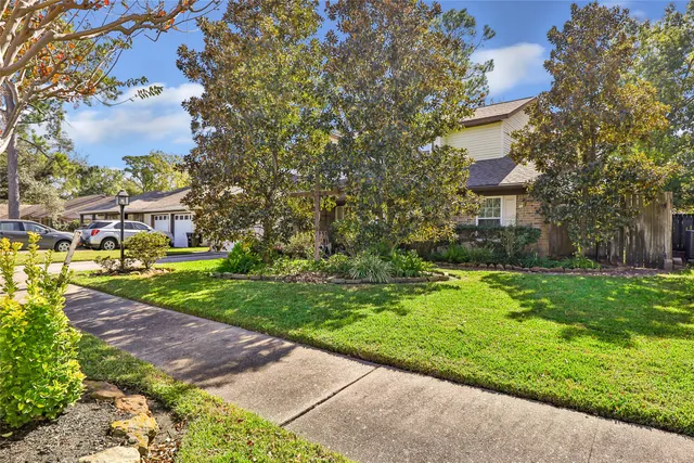 a view of a house with a big yard plants and large trees