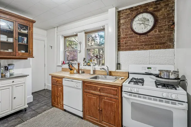 a kitchen with a stove a sink and a clock