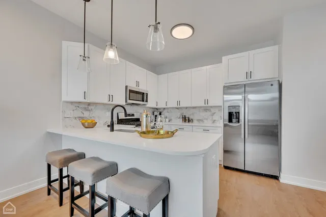 a kitchen with stainless steel appliances a table chairs and a refrigerator