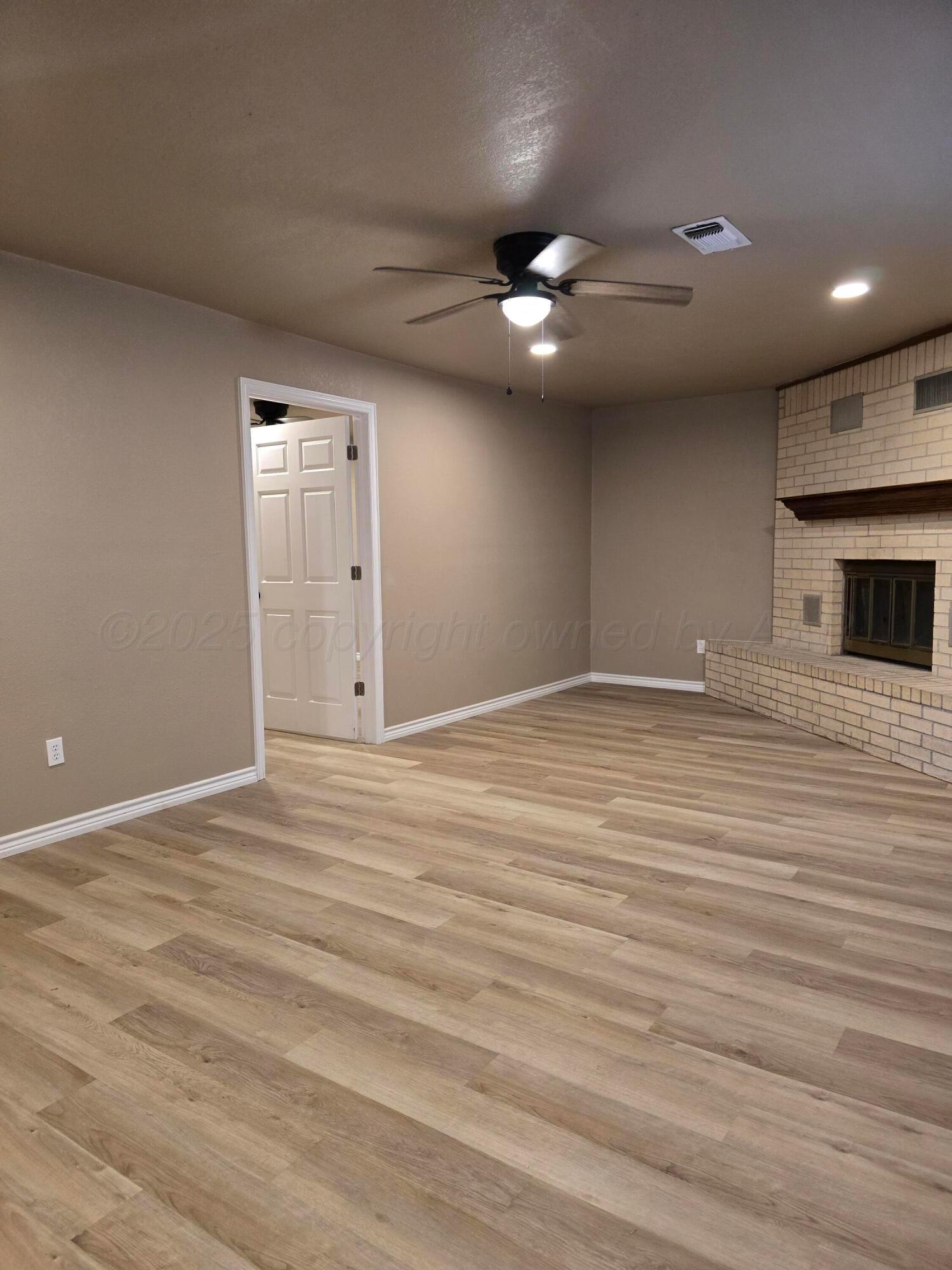 129 Pecan Street Borger, TX 79007 - Photo 11 of 23 a view of an empty room with wooden floor and a ceiling fan