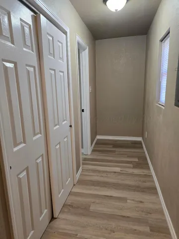 a view of a hallway with wooden floor and entryway