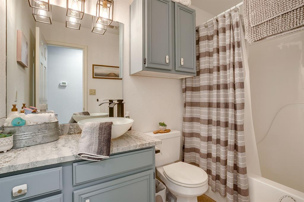3063 Hells Gate Loop, Unit 23 Strawn, TX 76475 - Photo 16 of 20 a bathroom with a granite countertop sink a toilet a mirror and shower curtain