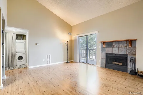an empty room with wooden floor fireplace and windows
