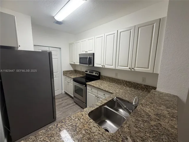 a kitchen with a refrigerator stove and white cabinets