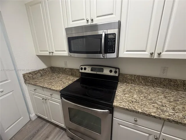 a kitchen with granite countertop white cabinets and stainless steel appliances