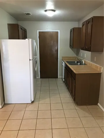 a kitchen with a sink a refrigerator and a stove top oven