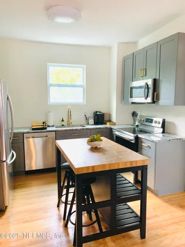 a kitchen with stainless steel appliances kitchen island granite countertop a sink a stove a table and chairs