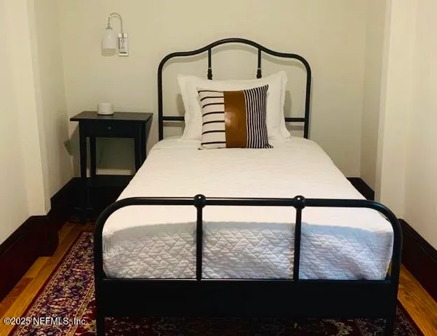 a bed sitting in a bedroom next to a window with potted plants on table