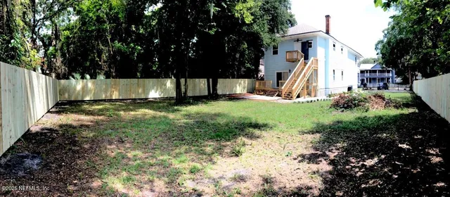 a view of a backyard with large trees and a barn