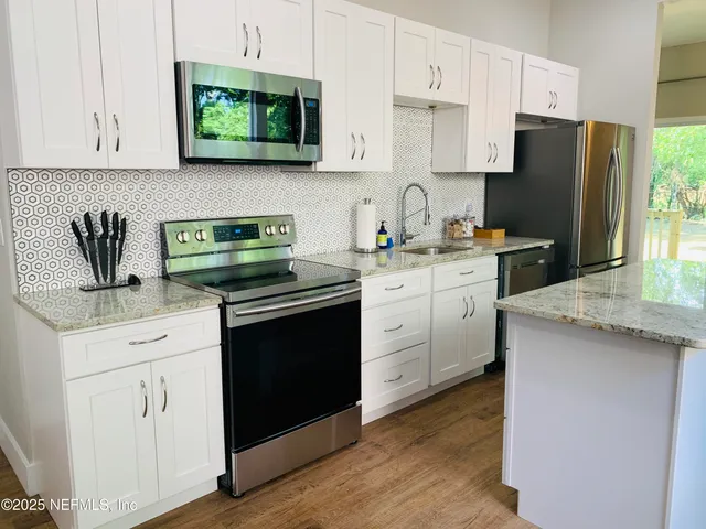 a kitchen with white cabinets sink and stainless steel appliances