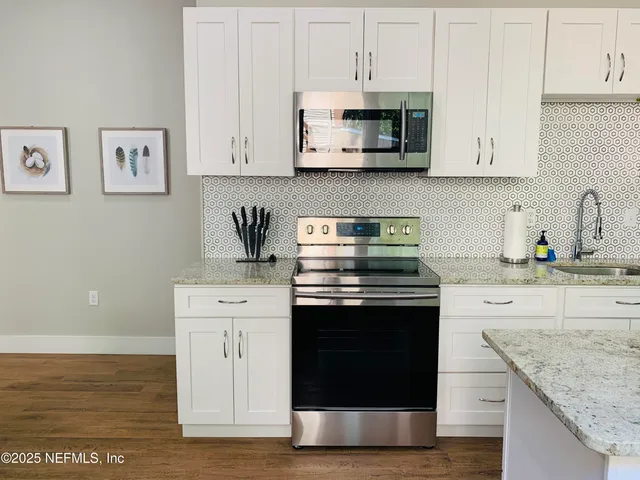 a kitchen with stainless steel appliances granite countertop a stove a sink and white cabinets