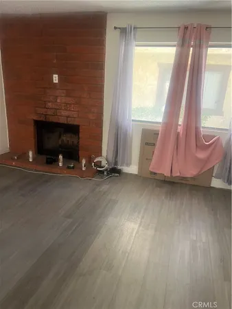 a view of an empty room with wooden floor and a fireplace