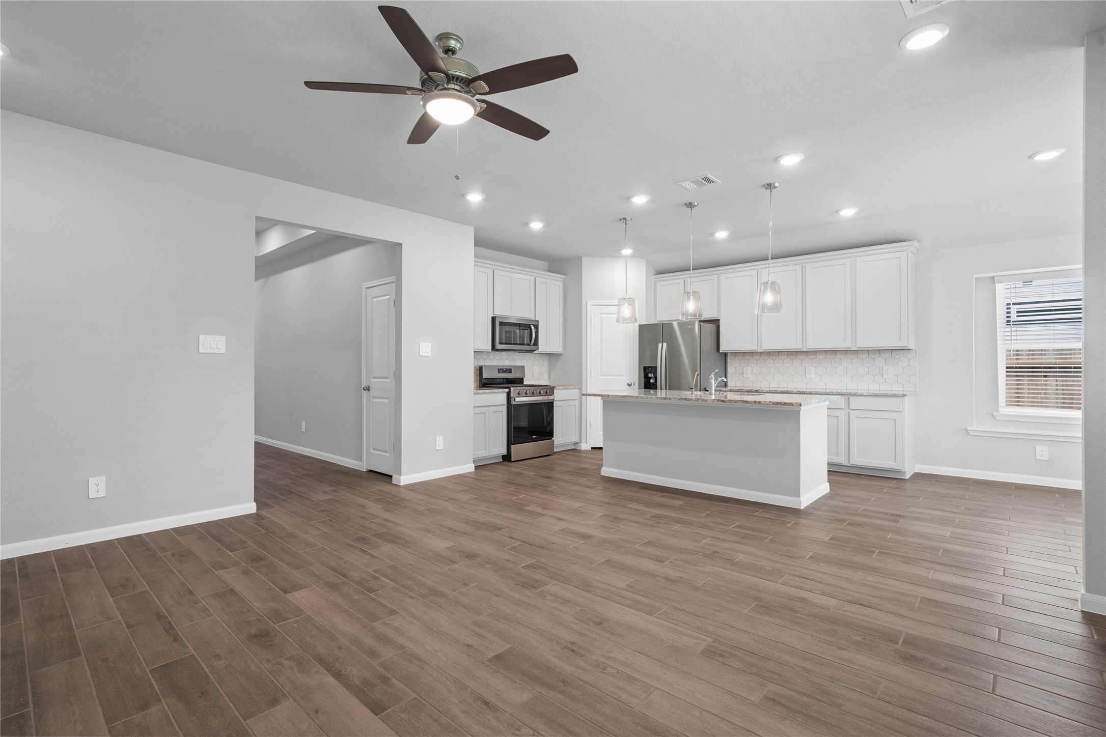 19645 Montgomery Rdg Way Montgomery, TX 77316 - Photo 26 of 41 This expansive view from Great Room showcases a seamless, open-concept layout that creates a warm and inviting path for guests, drawing the eye toward the hallway leading to the secondary bedrooms and entry.