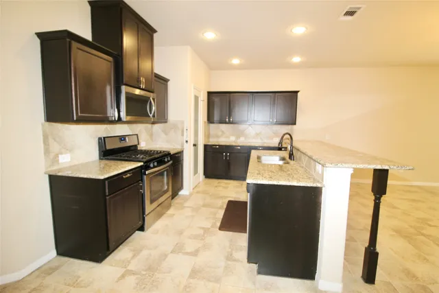 a kitchen with stainless steel appliances granite countertop a sink and a refrigerator