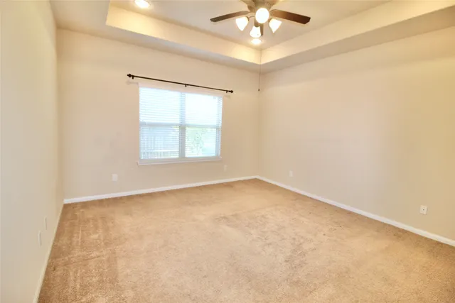 an empty room with a chandelier fan and windows