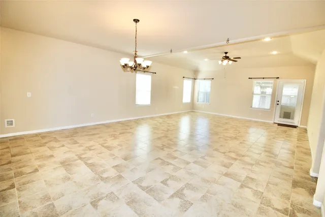 a view of an empty room and chandelier fan