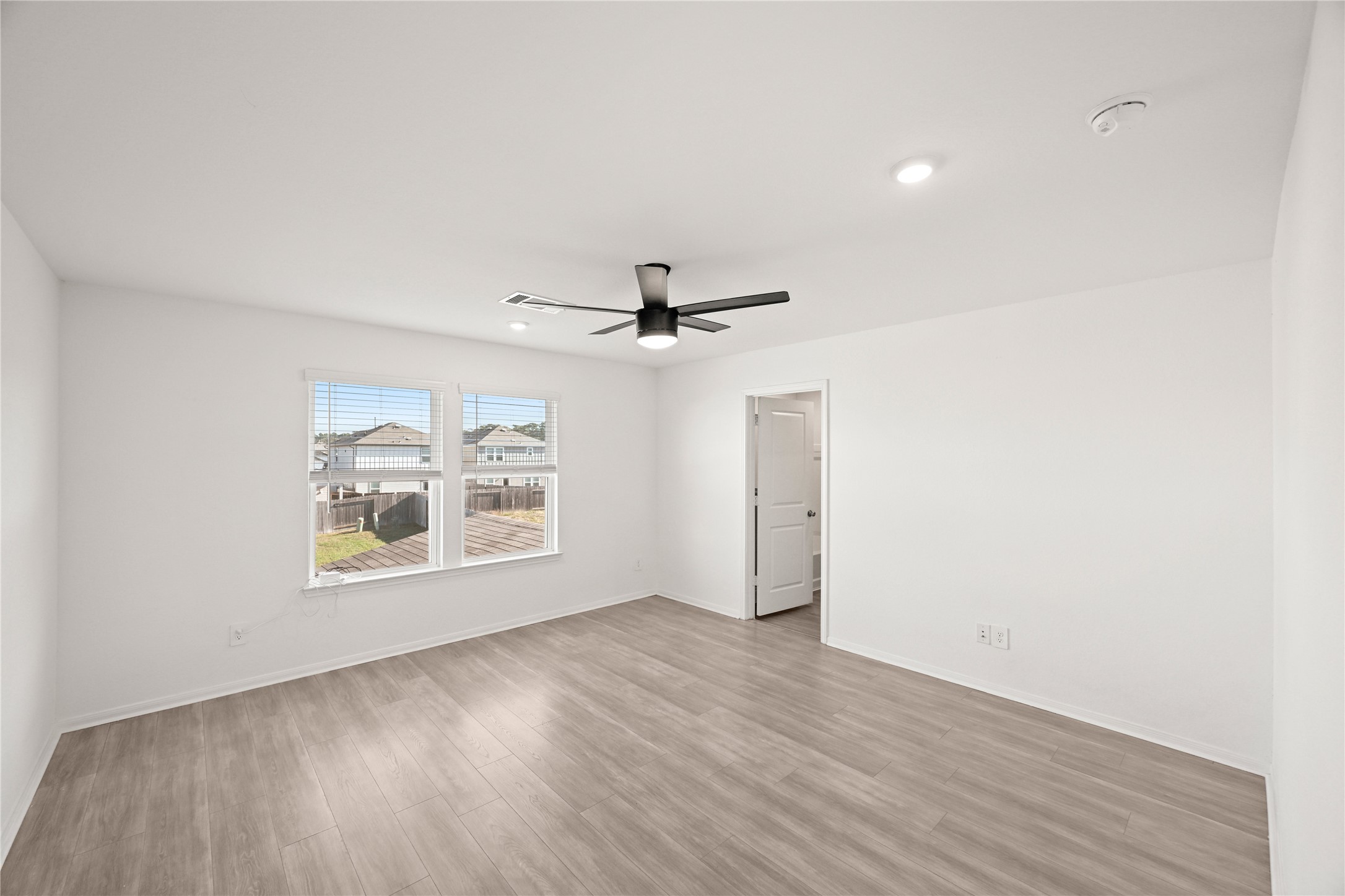 23442 Wrexham Street Spring, TX 77373 - Photo 11 of 33 an empty room with wooden floor ceiling fan and windows