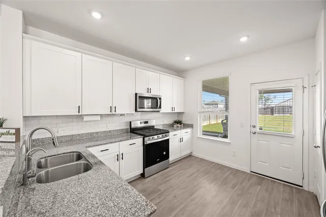 a kitchen with stainless steel appliances granite countertop a sink dishwasher stove and refrigerator