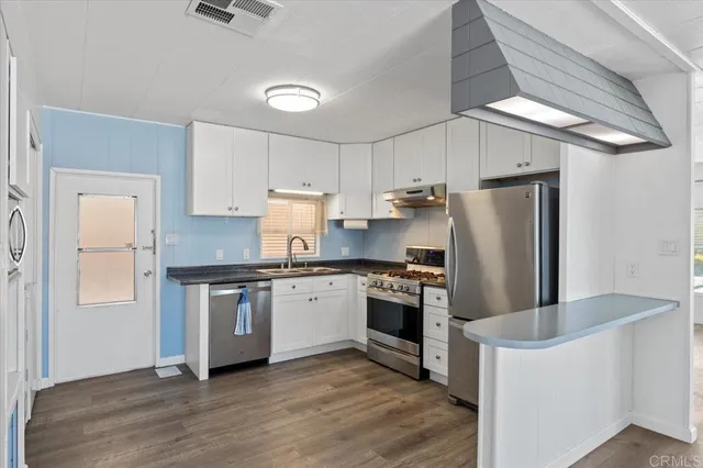 a kitchen with stainless steel appliances granite countertop a refrigerator a stove a sink and white cabinets