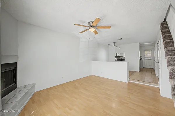 a view of empty room with wooden floor and fan