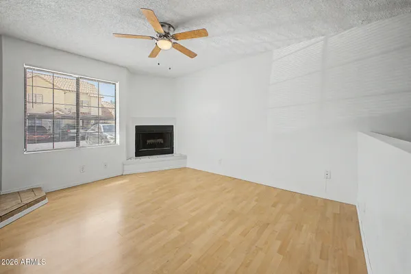 a view of an empty room with a window and a kitchen
