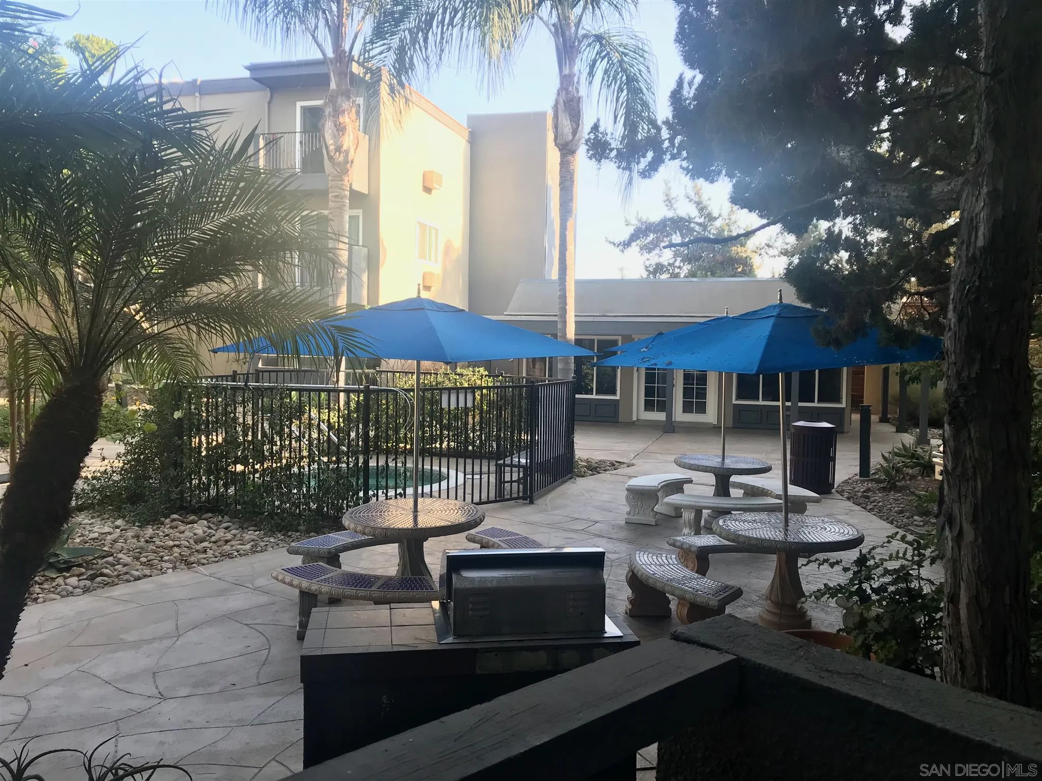 4860 Rolando Court, Unit 20 San Diego, CA 92115 - Photo 4 of 23 a view of a patio with couches table and chairs under an umbrella with a fire pit