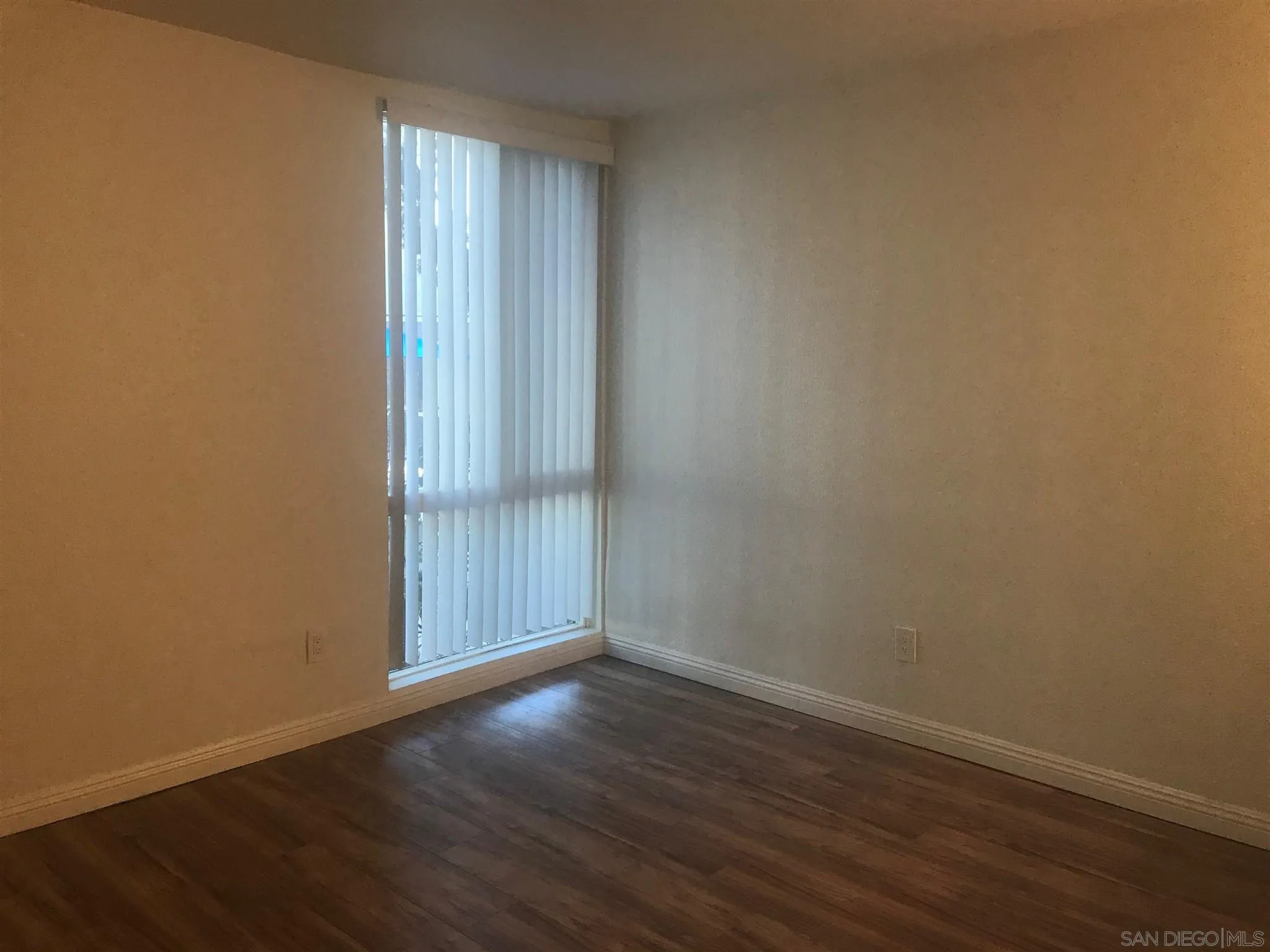 4860 Rolando Court, Unit 20 San Diego, CA 92115 - Photo 10 of 23 an empty room with wooden floor and windows with curtains