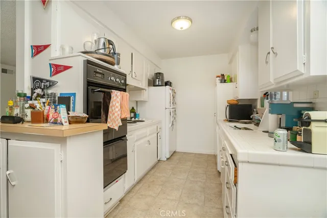 a kitchen that has a lot of white cabinets and stainless steel appliances
