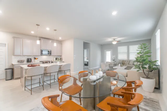 a living room with furniture kitchen view and a potted plant