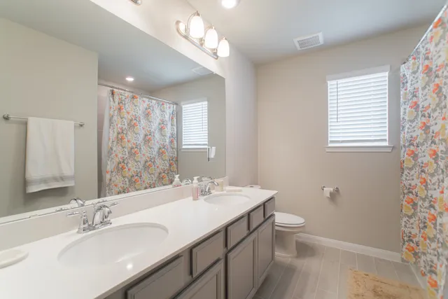 a bathroom with a double vanity sink mirror and toilet