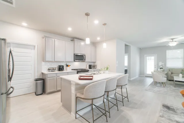 a open dining room with stainless steel appliances kitchen island granite countertop a sink a stove a dining table and chairs