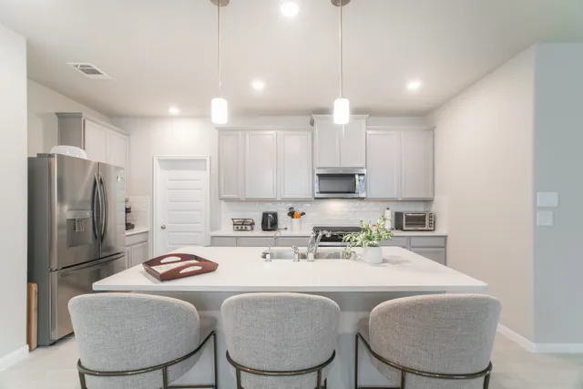 a kitchen with stainless steel appliances kitchen island granite countertop a sink a refrigerator and chairs