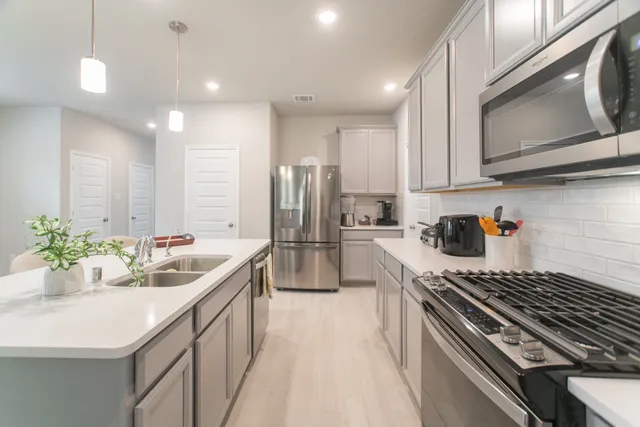 a kitchen with stainless steel appliances a sink a stove a refrigerator cabinets and a counter top space