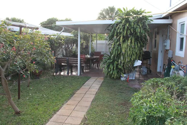 a view of a yard with plants and table and chairs under an umbrella