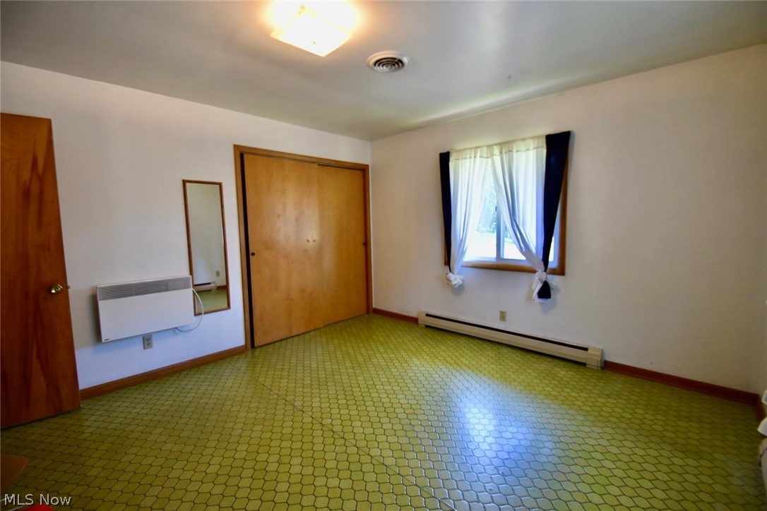 12840 South Reed Road Grafton, OH 44044 - Photo 17 of 27 Unfurnished bedroom with baseboard heating, a closet, tile floors, and radiator heating unit