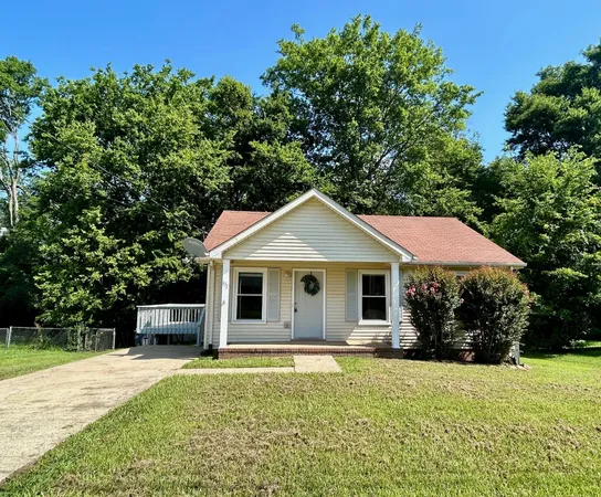 a front view of house with yard and trees in the background