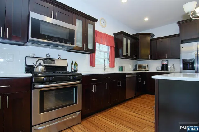 a kitchen with stainless steel appliances granite countertop a stove top oven a sink dishwasher a microwave oven and a cabinets with wooden floor