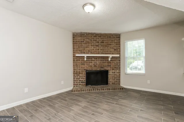 an empty room with wooden floor fireplace and windows
