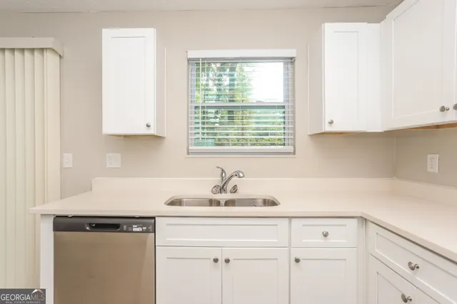 a kitchen with white cabinets and a window