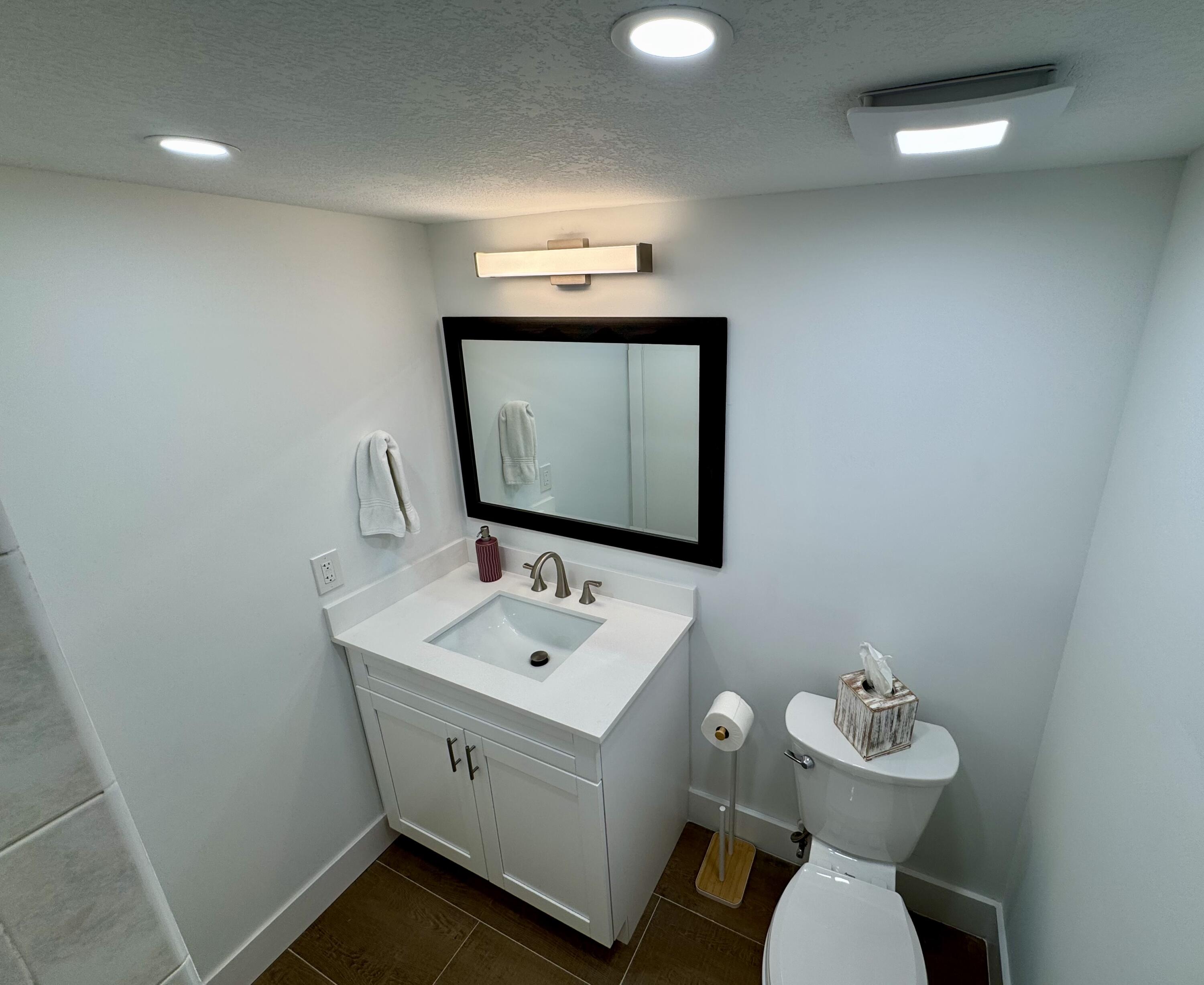 541 Normandy L Delray Beach, FL 33484 - Photo 15 of 55 a bathroom with a toilet sink and mirror