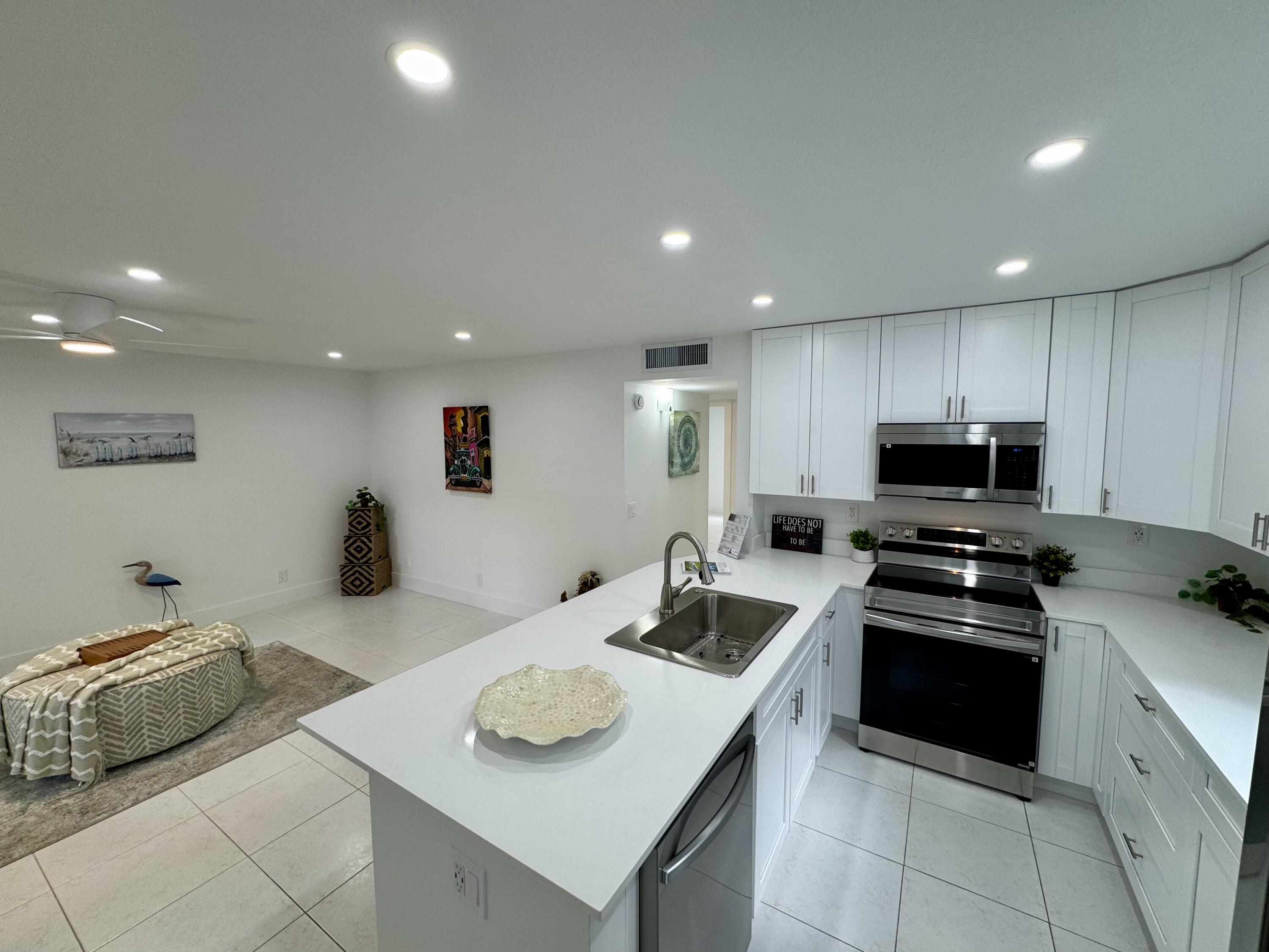 541 Normandy L Delray Beach, FL 33484 - Photo 55 of 55 a kitchen with a sink a stove and chairs
