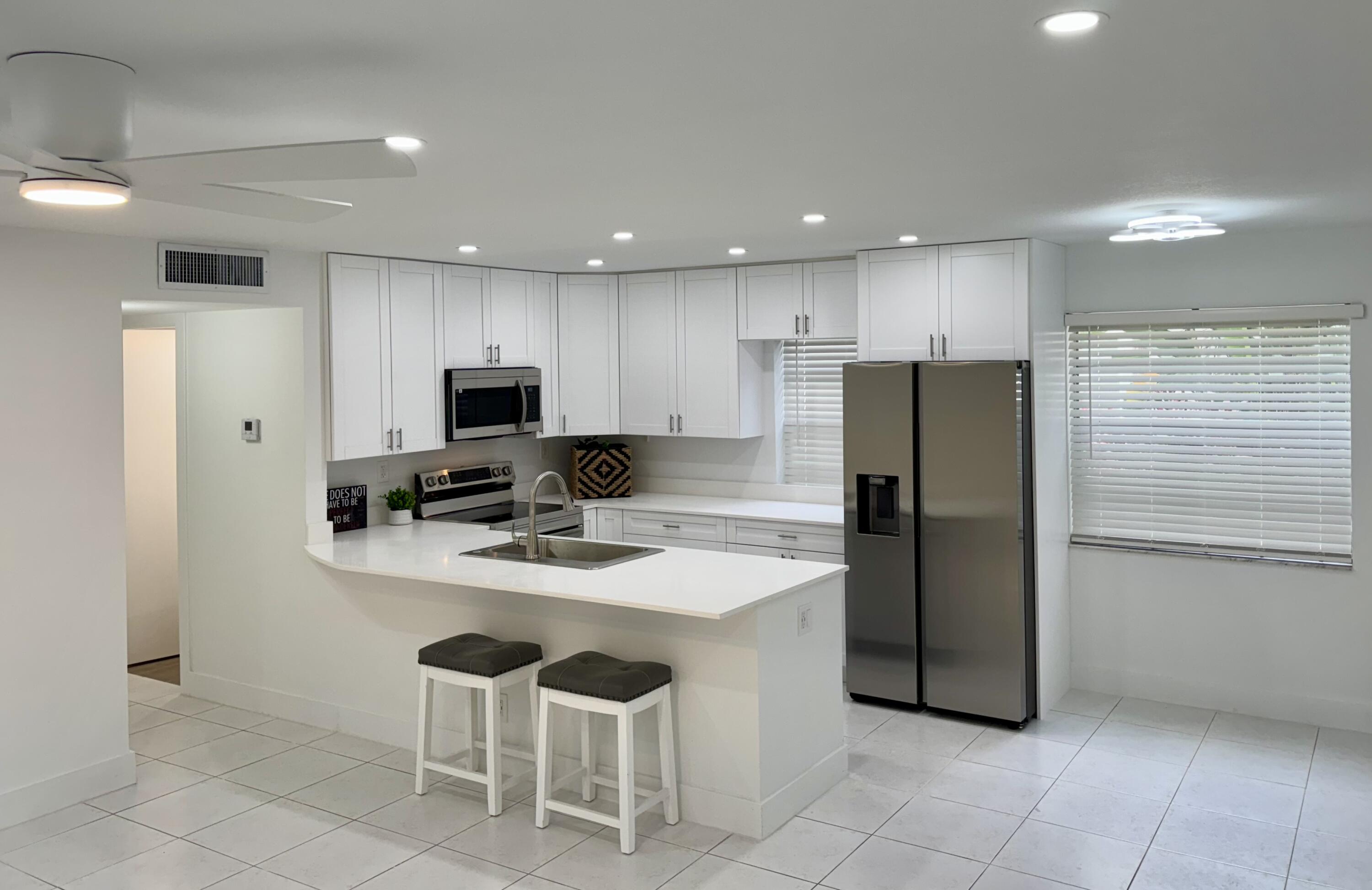 541 Normandy L Delray Beach, FL 33484 - Photo 3 of 55 a kitchen with a refrigerator a sink and chairs