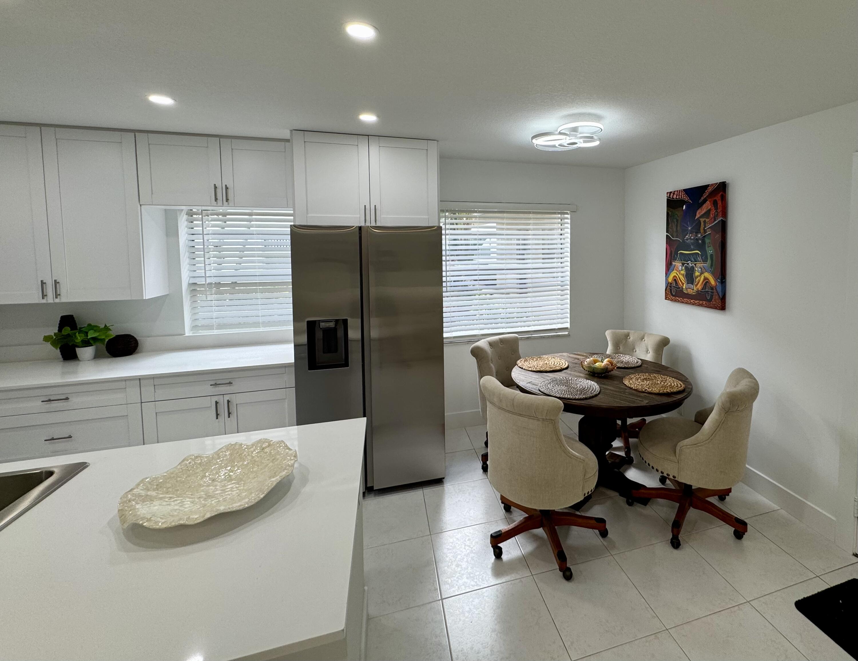 541 Normandy L Delray Beach, FL 33484 - Photo 4 of 55 a kitchen with stainless steel appliances a refrigerator a sink a stove a dining table and chairs
