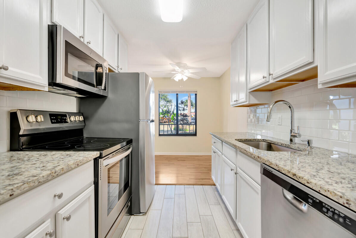 150 Pineview Road, Unit B2 Jupiter, FL 33469 - Photo 6 of 13 a kitchen with granite countertop a sink dishwasher stove and cabinets with wooden floor