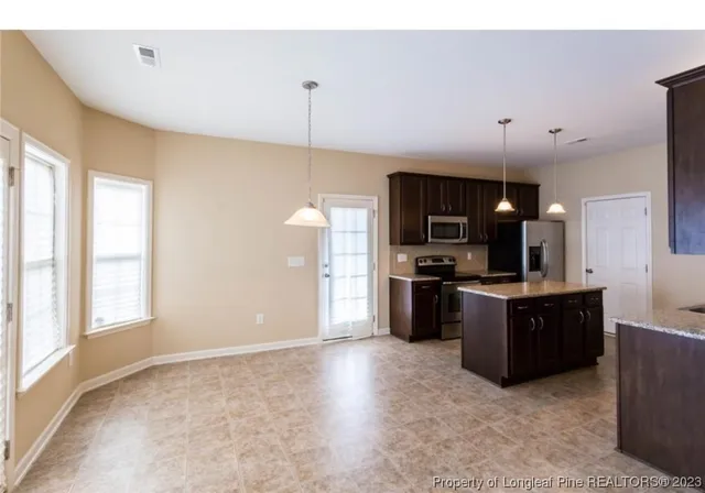 a kitchen with stainless steel appliances granite countertop a refrigerator a sink a stove and microwave