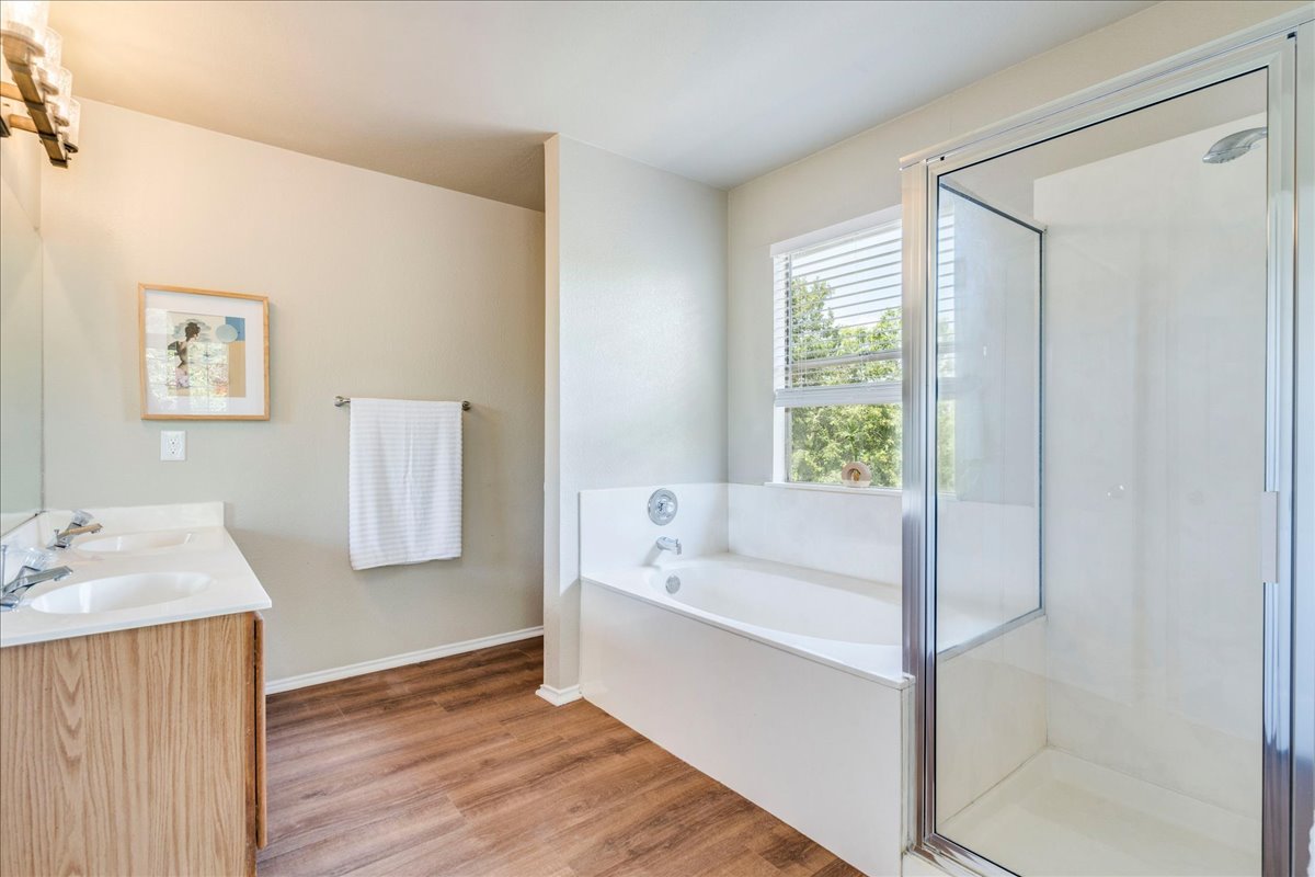 9300 Tea Rose Trail Austin, TX 78748 - Photo 21 of 33 A well-lit bathroom features a large tub beneath a window and a separate shower, complemented by a vanity with dual sinks.