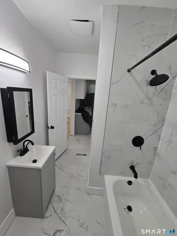 a bathroom with a tub a sink and mirror